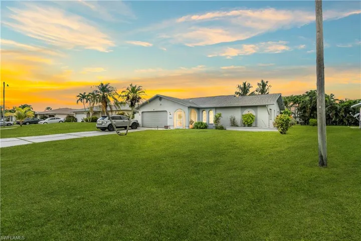 Ranch-style home with concrete driveway, a front yard, an attached garage, and stucco siding