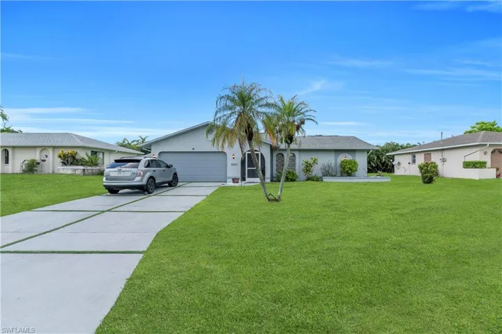 Ranch-style house with driveway, a front lawn, a garage, and stucco siding