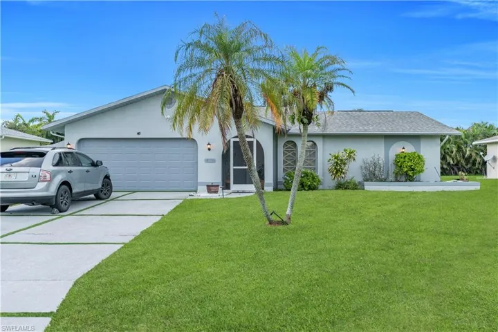 Ranch-style home featuring stucco siding, an attached garage, driveway, a front lawn, and roof with shingles