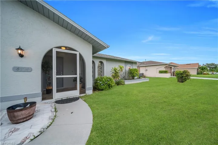 Doorway to property with stucco siding and a lawn