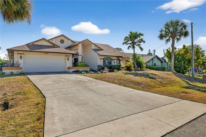 View of front of house featuring stucco siding, a front lawn, driveway, and a garage