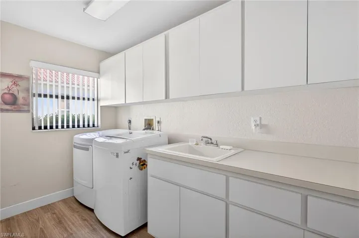 Laundry area with light wood finished floors, cabinet space, and separate washer and dryer
