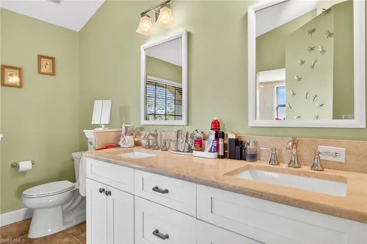 Bathroom featuring double vanity and dark tile patterned flooring