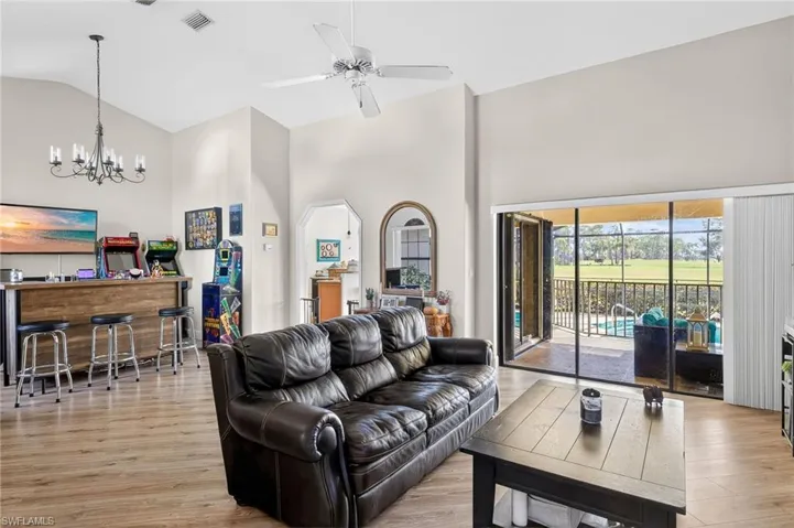 Living room featuring light wood-style flooring, lofted ceiling, ceiling fan, and hanging lights