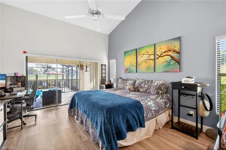 Bedroom featuring a desk, access to outside, wood finished floors, vaulted ceiling, and ceiling fan