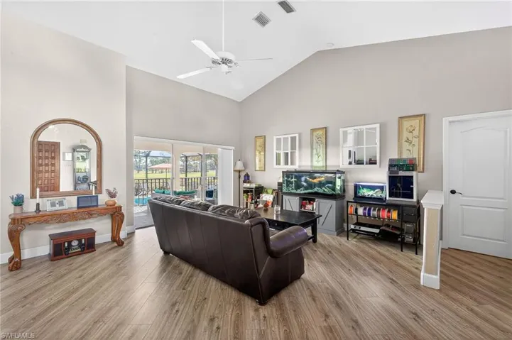 Living room featuring light wood-style flooring, vaulted ceiling, and ceiling fan