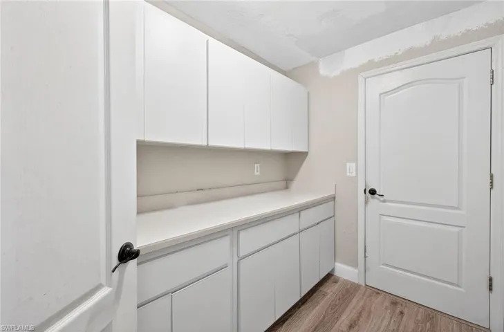 Bar area featuring white cabinetry, light countertops, and light wood-style floors