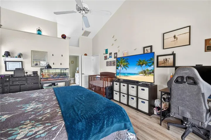 Bedroom with light wood-style flooring, ceiling fan, a desk, and vaulted ceiling
