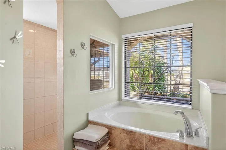 Full bath featuring a garden tub, a walk in shower, and vaulted ceiling