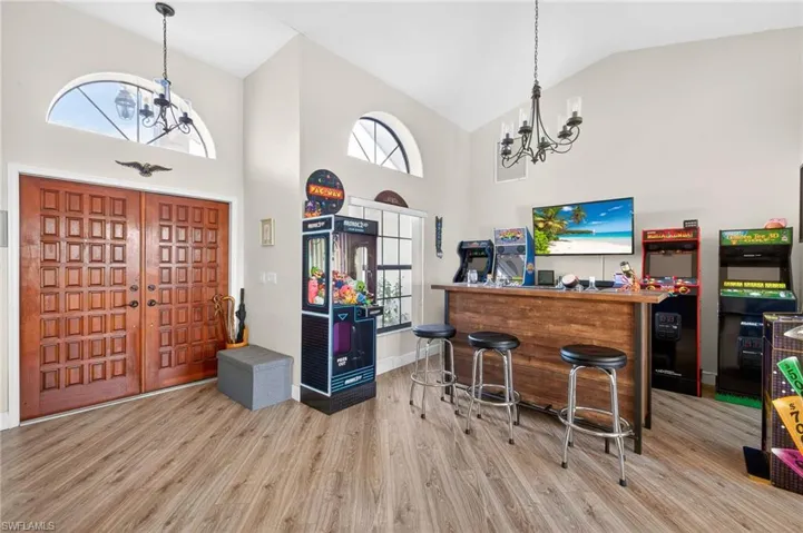Entryway featuring a chandelier, wood finished floors, vaulted ceiling, and healthy amount of natural light
