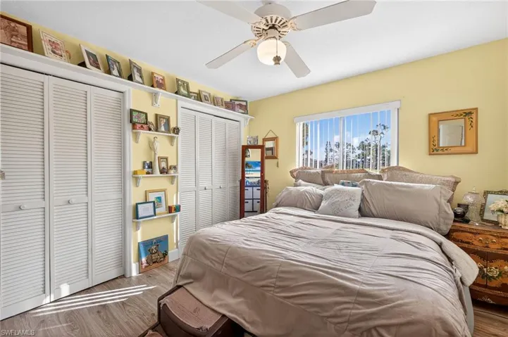 Bedroom with two closets, wood finished floors, and a ceiling fan