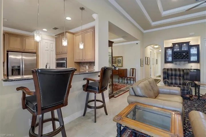 Kitchen with a breakfast bar, backsplash, decorative light fixtures, appliances with stainless steel finishes, and light tile patterned floors