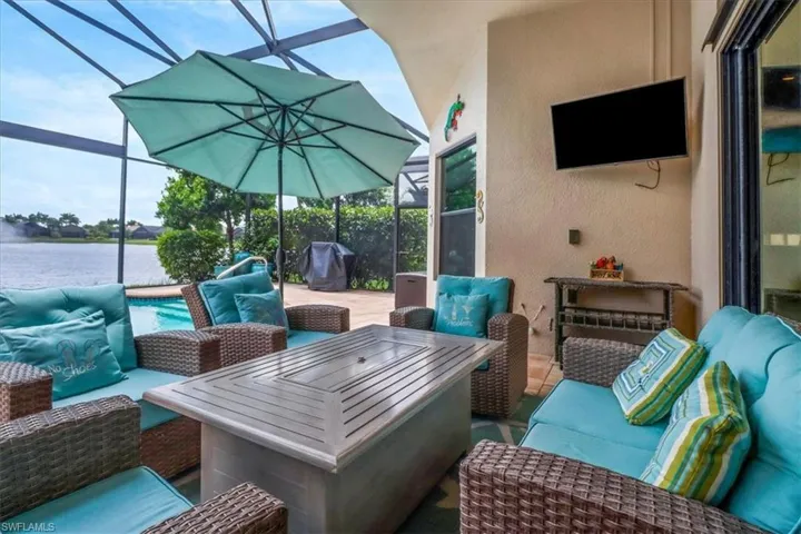 View of patio featuring glass enclosure, outdoor lounge area, and a water view