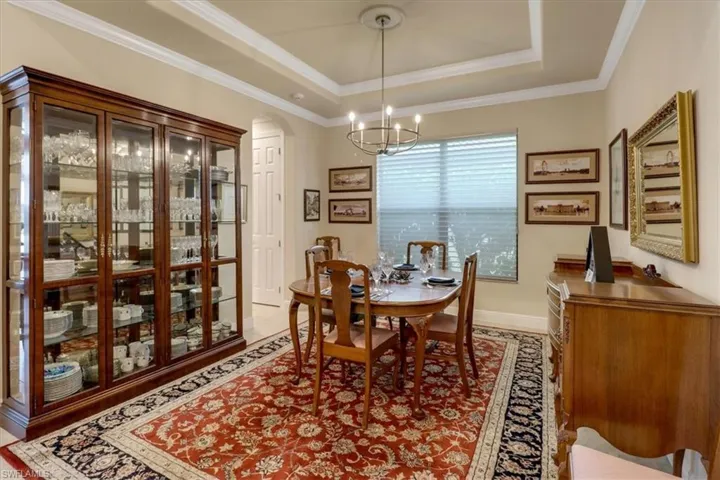 Dining room with a tray ceiling, crown molding, and a chandelier