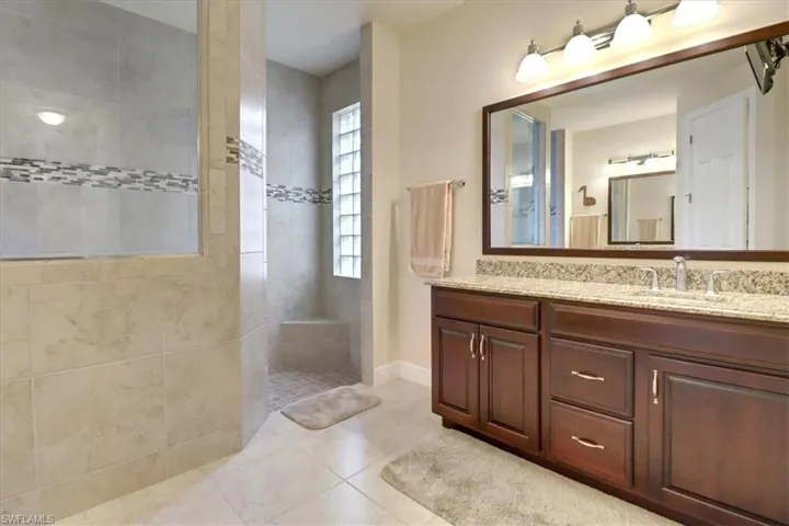 Bathroom featuring tile patterned floors, vanity, and tiled shower