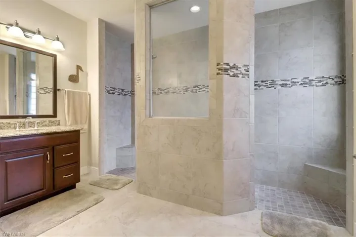 Bathroom with tiled shower, tile patterned flooring, and vanity