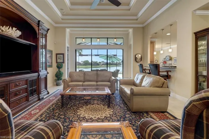 Living room with ceiling fan, crown molding, and a tray ceiling