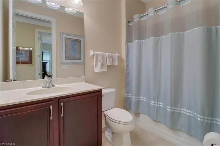 Full bathroom with tile patterned floors, shower / bath combo with shower curtain, vanity, and toilet