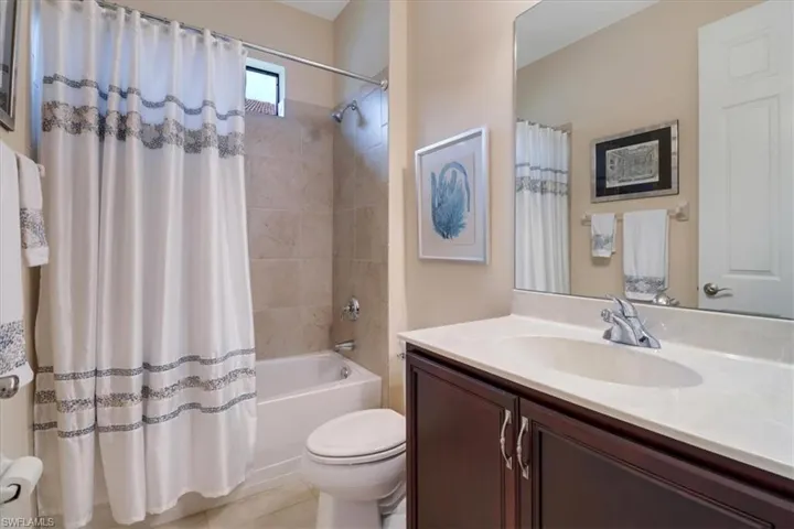 Full bathroom featuring vanity, shower / bathtub combination with curtain, and toilet