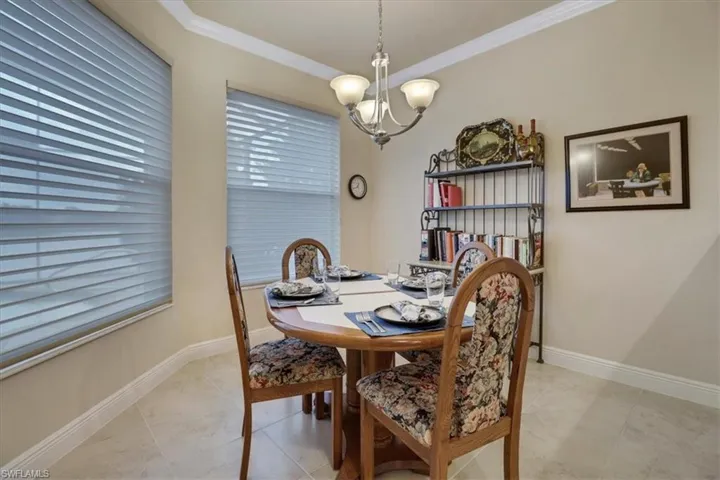 Dining space with ornamental molding, an inviting chandelier, and light tile patterned floors