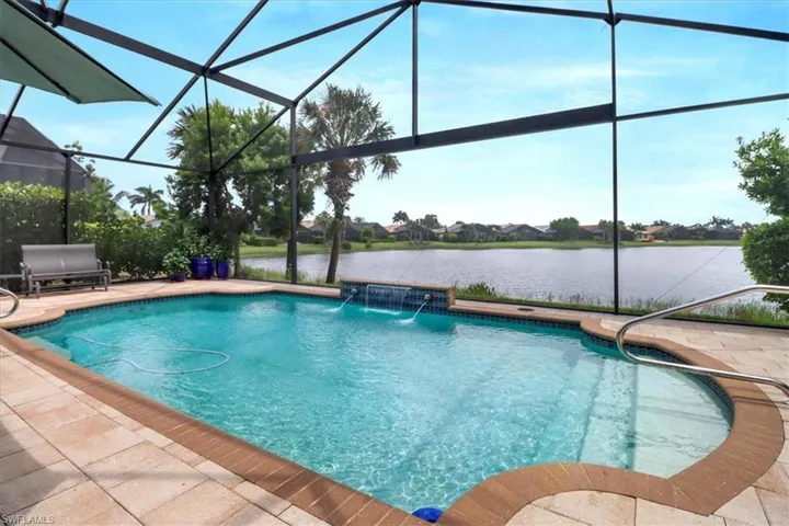 View of pool with glass enclosure, pool water feature, and a patio