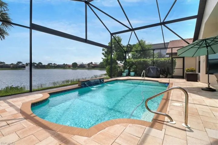 View of swimming pool featuring a water view, a lanai, pool water feature, and a patio