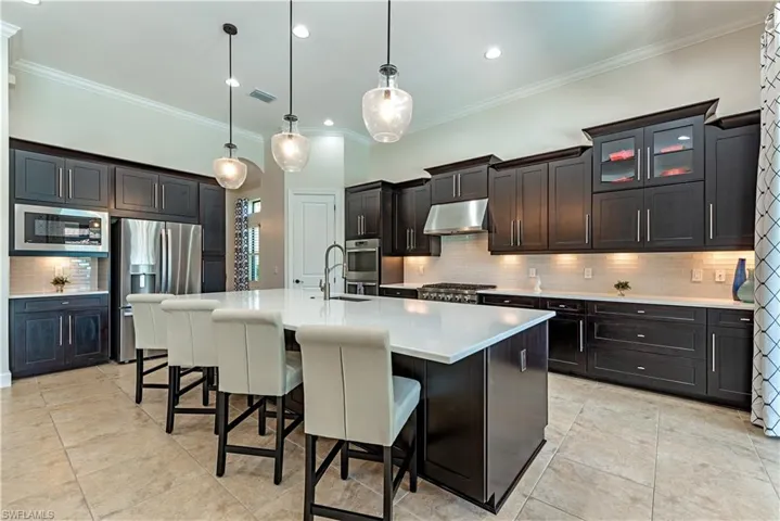 Kitchen with decorative light fixtures, stainless steel appliances, and tasteful backsplash