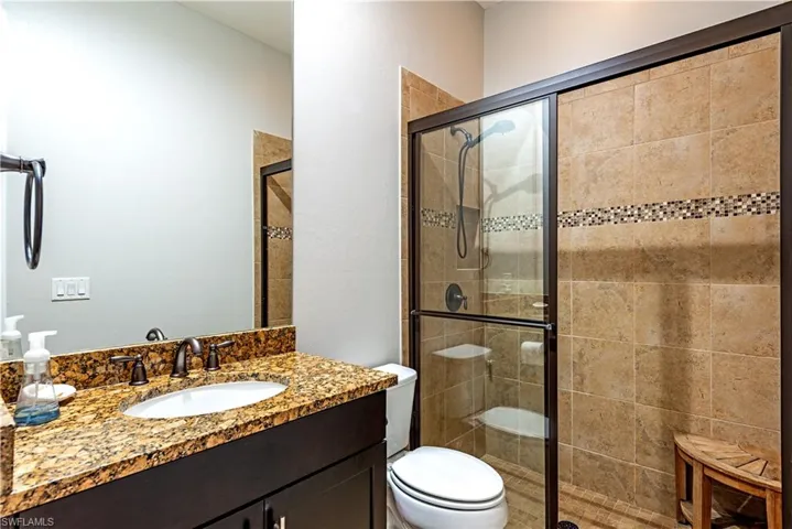Bathroom featuring vanity, toilet, and a shower with door