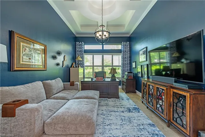 Tiled home office with ornamental molding, a tray ceiling, and a chandelier