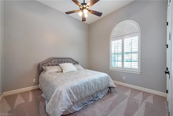 Bedroom featuring carpet, ceiling fan, and vaulted ceiling