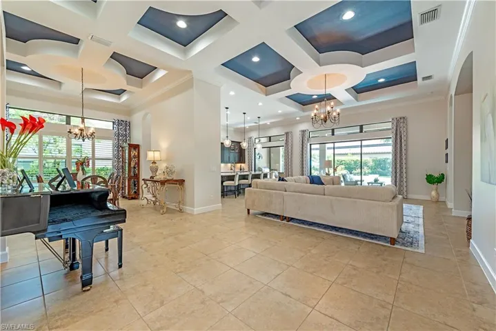Living room with a healthy amount of sunlight, coffered ceiling, and an inviting chandelier