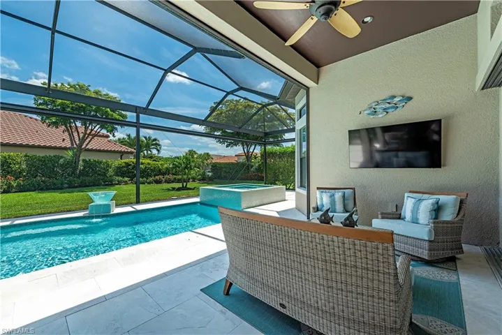 View of swimming pool featuring ceiling fan, a patio area, glass enclosure, and an in ground hot tub