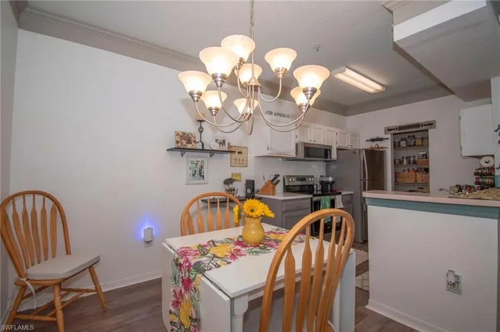 Dining room featuring dark wood-type flooring, a chandelier, and ornamental molding
