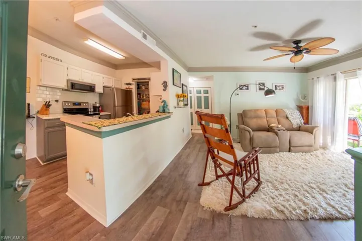 Kitchen with stainless steel appliances, white cabinetry, tasteful backsplash, wood-type flooring, and ceiling fan