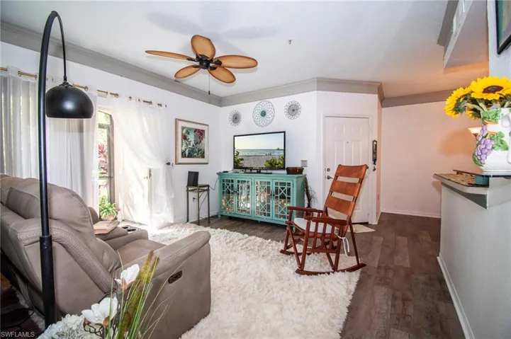Living room with ceiling fan, crown molding, and dark hardwood / wood-style flooring