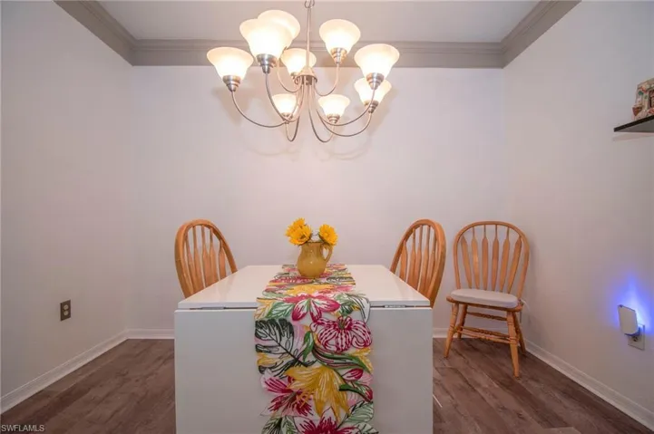 Dining area featuring ornamental molding, an inviting chandelier, and dark hardwood / wood-style floors
