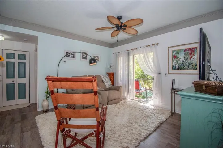 Living room featuring ceiling fan, dark wood-type flooring, and ornamental molding