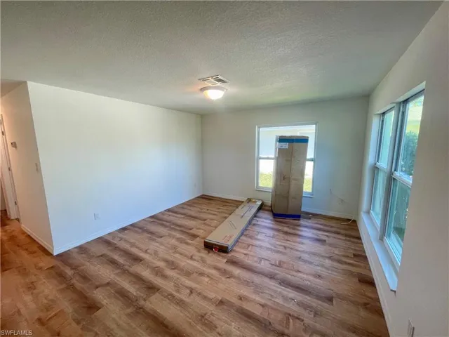 Unfurnished room with light hardwood / wood-style flooring and a textured ceiling