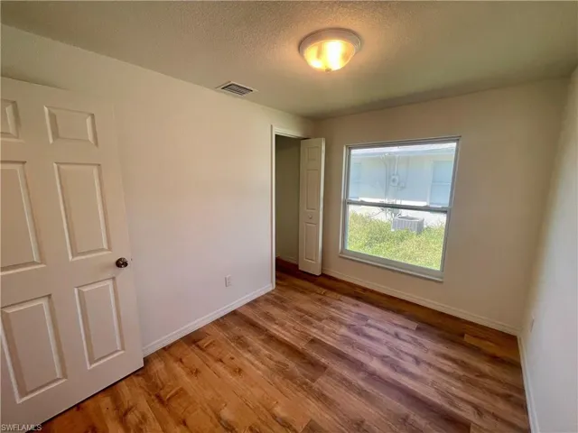 Unfurnished bedroom featuring hardwood / wood-style floors and a textured ceiling