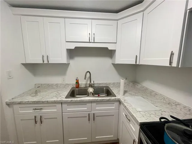 Kitchen featuring electric range, sink, and white cabinets