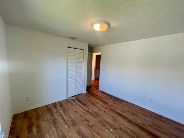 Unfurnished bedroom with wood-type flooring, a textured ceiling, and a closet