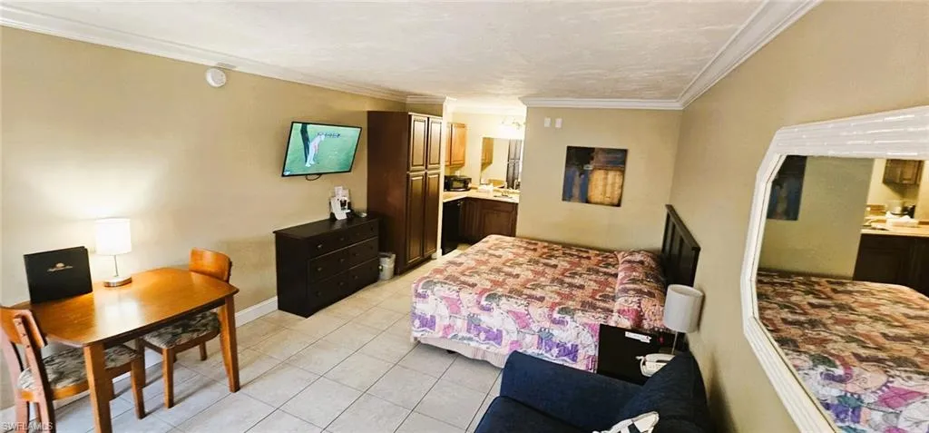 Bedroom with ensuite bathroom, light tile patterned floors, and crown molding
