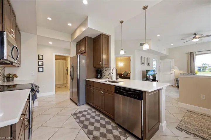 Kitchen featuring pendant lighting, stainless steel appliances, decorative backsplash, light tile patterned floors, and recessed lighting