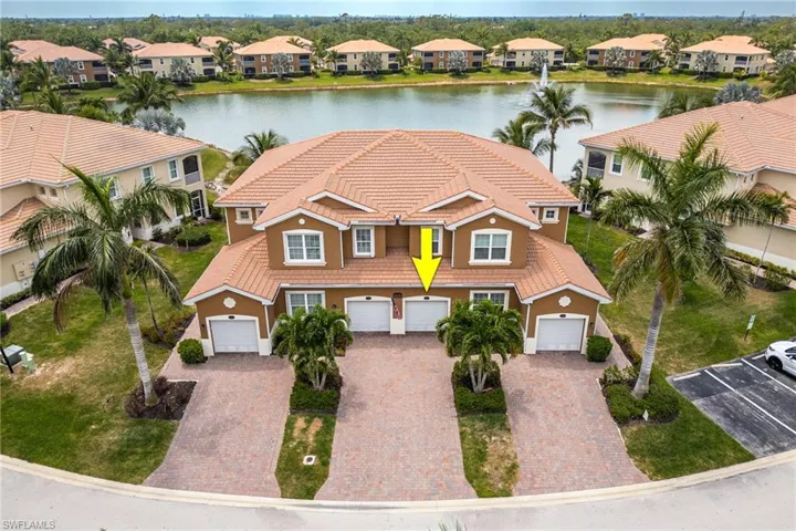View of front of home featuring a water view, a tiled roof, stucco siding, and driveway