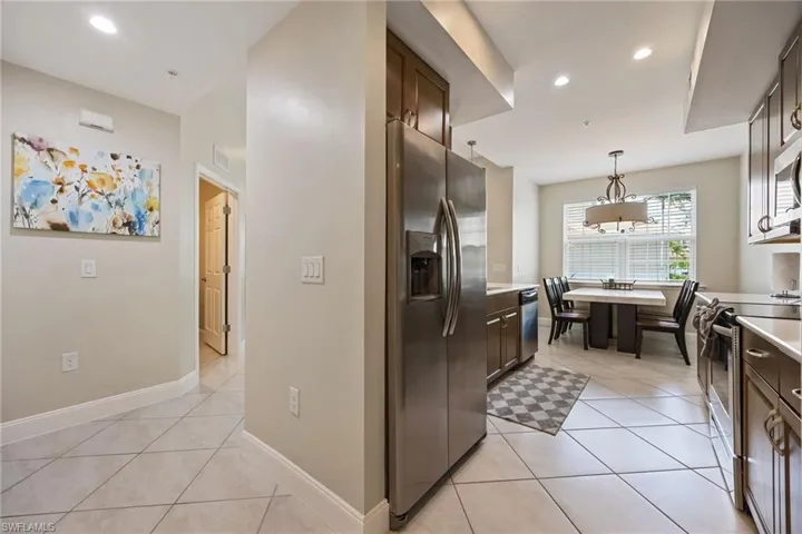Kitchen featuring dark brown cabinetry, stainless steel appliances, light tile patterned floors, pendant lighting, and recessed lighting