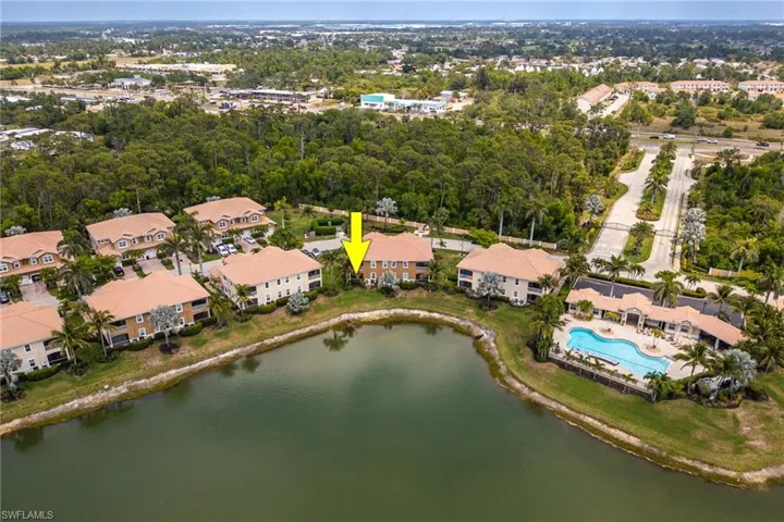 Aerial view of property and surrounding area with a nearby body of water and a tree filled landscape