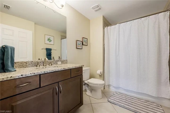 Full bathroom with vanity, light tile patterned floors, and Guest shower / bath combination with curtain