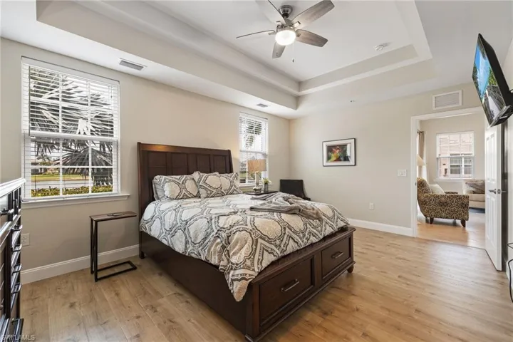 Bedroom featuring a raised ceiling, light wood-type flooring, and a ceiling fan