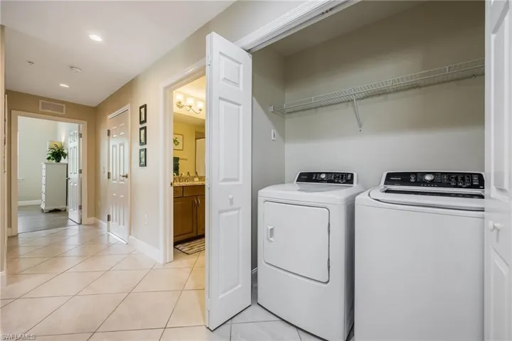 Laundry area featuring light tile patterned flooring, washer and clothes dryer, and recessed lighting