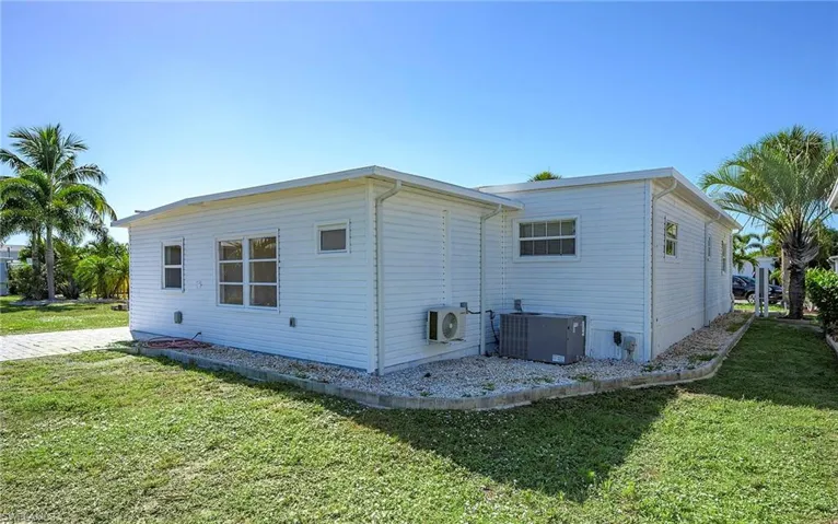 Rear view of property with central AC unit and a lawn
